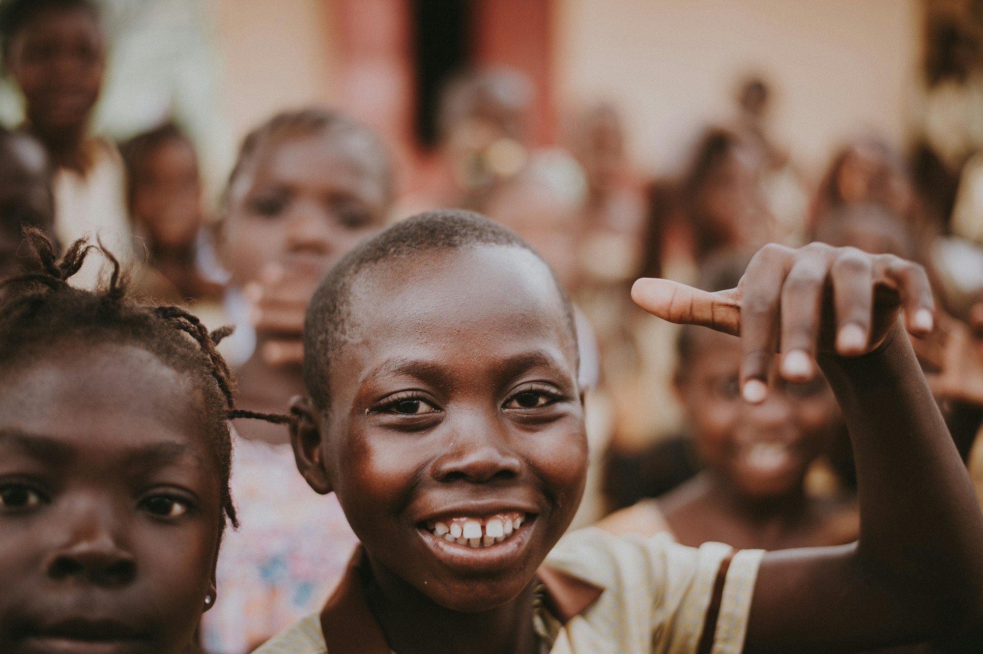A boy smiling, surrounded by children